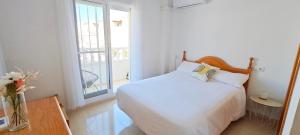 a white bedroom with a bed and a window at Casa Mediterránea Kai in Gran Alacant
