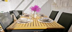 a wooden table with plates and glasses and flowers on it at Casa Mediterránea Kai in Gran Alacant
