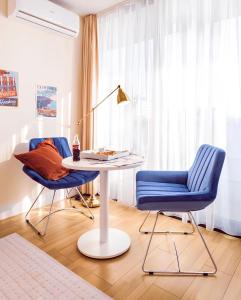a living room with a table and two blue chairs at Panorama Black Sea View Sunset Hotel in Batumi