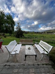 two white benches sitting next to a picnic table at el corazón del cerro in Melipilla +9 photos