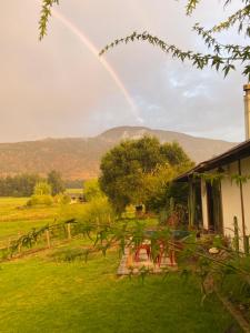 a rainbow in the sky over a yard with a house at el corazón del cerro in Melipilla