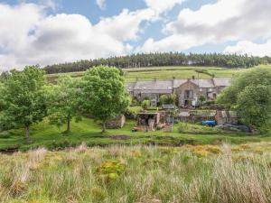 an old farmhouse on a hill with trees at Englewood Cottage in Hexham