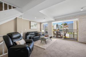 a living room with black leather furniture and a balcony at Ocean Shores 1 in South West Rocks