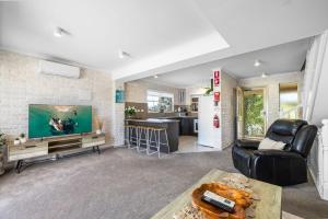 a living room with a large television and a kitchen at Ocean Shores 1 in South West Rocks