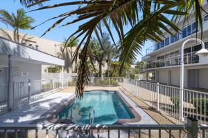 a swimming pool with a palm tree in front of a building at Ocean Shores 1 in South West Rocks