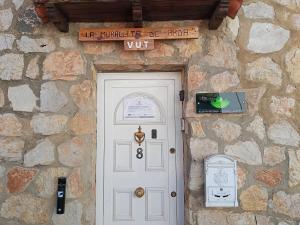 a stone building with a white door and a sign above it at La murallita de Aroa in Cañete +12 photos