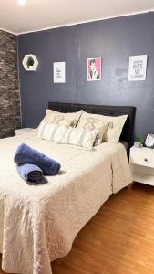 a bedroom with a large bed with a blue wall at Minidepto temuco in Temuco +24 photos