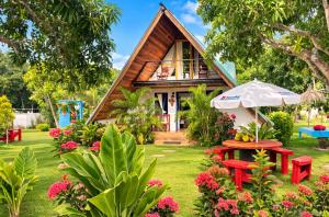 a house with a garden with red benches and an umbrella at Dreamvilles Ecovillage Eco Villas with Jacuzzi near Beaches in Las Galeras