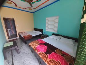 two beds in a room with blue walls at Chaukhamba view stay in Gupta Kāshi