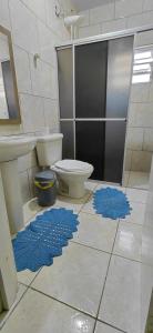 a bathroom with a toilet and blue mats on the floor at Pousada familiar 02 in Rio do Sul