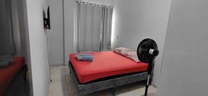 a small red bed in a room with a fan at Pousada familiar 02 in Rio do Sul