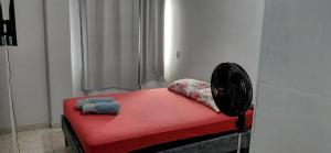 a small red bed with two pillows and a fan at Pousada familiar 02 in Rio do Sul