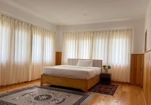 a bedroom with a bed and large windows at Sompal Service Apartment in Paro