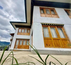 a white building with wooden doors and windows at Sompal Service Apartment in Paro
