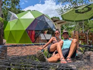 a man and woman sitting on a net in front of a tent at The Tortoise Dome Lodge in Bellavista +30 photos