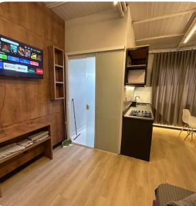 a living room with a kitchen and a tv at Studios Botânico in Curitiba