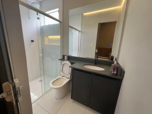 a bathroom with a toilet and a sink and a mirror at Studios Botânico in Curitiba