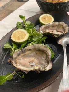 two oysters on a black plate with lettuce and lime slices at Four Rooms Luxury Suite in Palermo