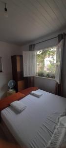 a bedroom with a large white bed with a window at O Pouso Condomínio in Mucugê