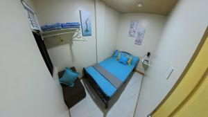 a small room with a bed with blue sheets and pillows at CLBC Residences 1A in Ibaba