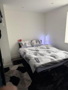 a bedroom with a bed with a black and white comforter at Holiday Haven in Potters Bar