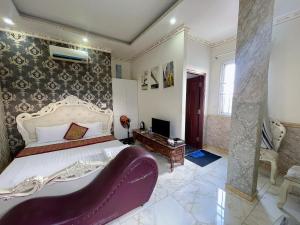 a bedroom with a large bed with a purple chair at King hotel in Dĩ An