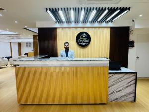 a man standing behind a counter in an office at Crystal Heritage Inn in Dhaka