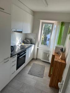 a kitchen with white cabinets and a sink and a window at Cosy Apartment in Aadorf