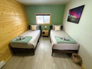 two twin beds in a room with green walls at Caribou Cottage in Churchill