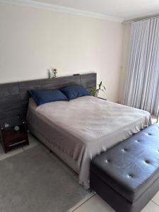 a bedroom with a large bed and a blue ottoman at Moto GP sobrado in Goiânia