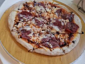 a pizza sitting on top of a wooden cutting board at Wanderlust Bed and Breakfast Puerto Princesa in Puerto Princesa City