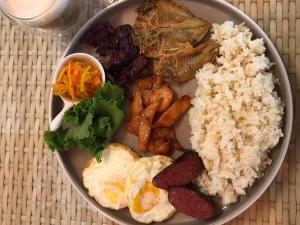 a plate of food with rice and meat and vegetables at Wanderlust Bed and Breakfast Puerto Princesa in Puerto Princesa City