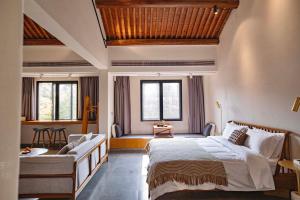 a bedroom with a bed and a couch and windows at Sanfuyizhai Homestay in Taizhou