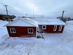 a small red house with snow on the roof at Beluga Beach House in Churchill