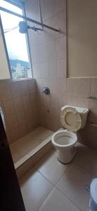 a bathroom with a toilet and a shower and a window at Hostal home 3 in Quito