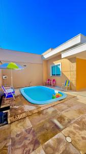 a large swimming pool with chairs and an umbrella at CASA MARIANNA em Paracuru - Piscina, 3 quartos, ar condicionado e perto de tudo! in Paracuru