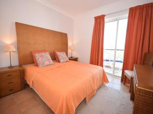 a bedroom with a bed with an orange bedspread and a window at Sunny Balcony Apartment and Pool in Vilamoura +32 photos