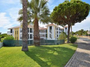 a white building with palm trees in front of it at Sunny Balcony Apartment and Pool in Vilamoura