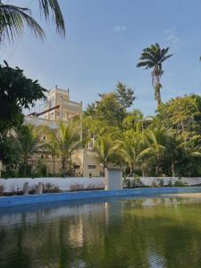 a building with palm trees and a swimming pool at Hotel Pousada Vila da Natureza in Maceió
