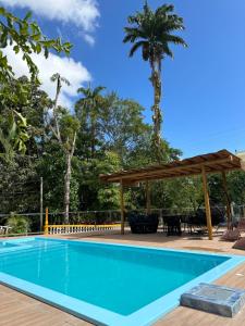 a swimming pool with a pergola and palm trees at Hotel Pousada Vila da Natureza in Maceió