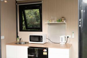 a kitchen with a microwave and a sink and a window at Sweet Hart 2 by Tiny Away in Tamahere