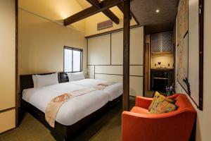 a bedroom with a large bed and a chair at The Machiya Kamiumeya in Kyoto