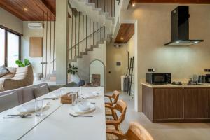 a kitchen and living room with a table and chairs at Unwind Villa by Betterplace in Canggu