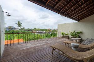a wooden deck with chairs and a view of the ocean at Unwind Villa by Betterplace in Canggu
