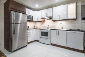 a kitchen with white cabinets and a stainless steel refrigerator at Appartement 2 chambres, centre ville, séjour longue durée in Quebec City