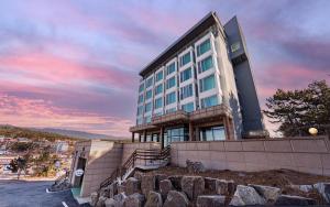 a building on top of a hill with a sunset at Incheon The Rest Hotel in Incheon