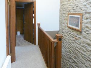 a hallway with a staircase with a stone wall at Hollin Bank Cottage in Salterforth