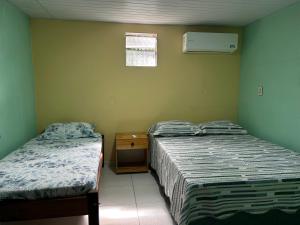 a bedroom with two beds and a nightstand and a window at Quarto Sairé in Santarém