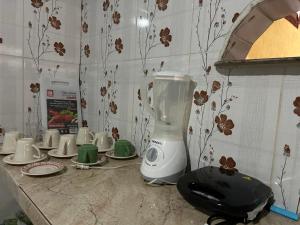 a kitchen counter with a blender and cups and plates at Quarto Sairé in Santarém