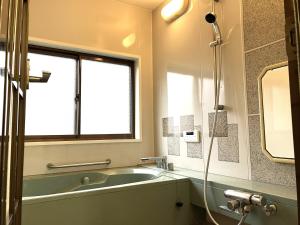 a bathroom with a bath tub and a window at ゲストハウスわたうさぎ in Tsuruoka +72 photos